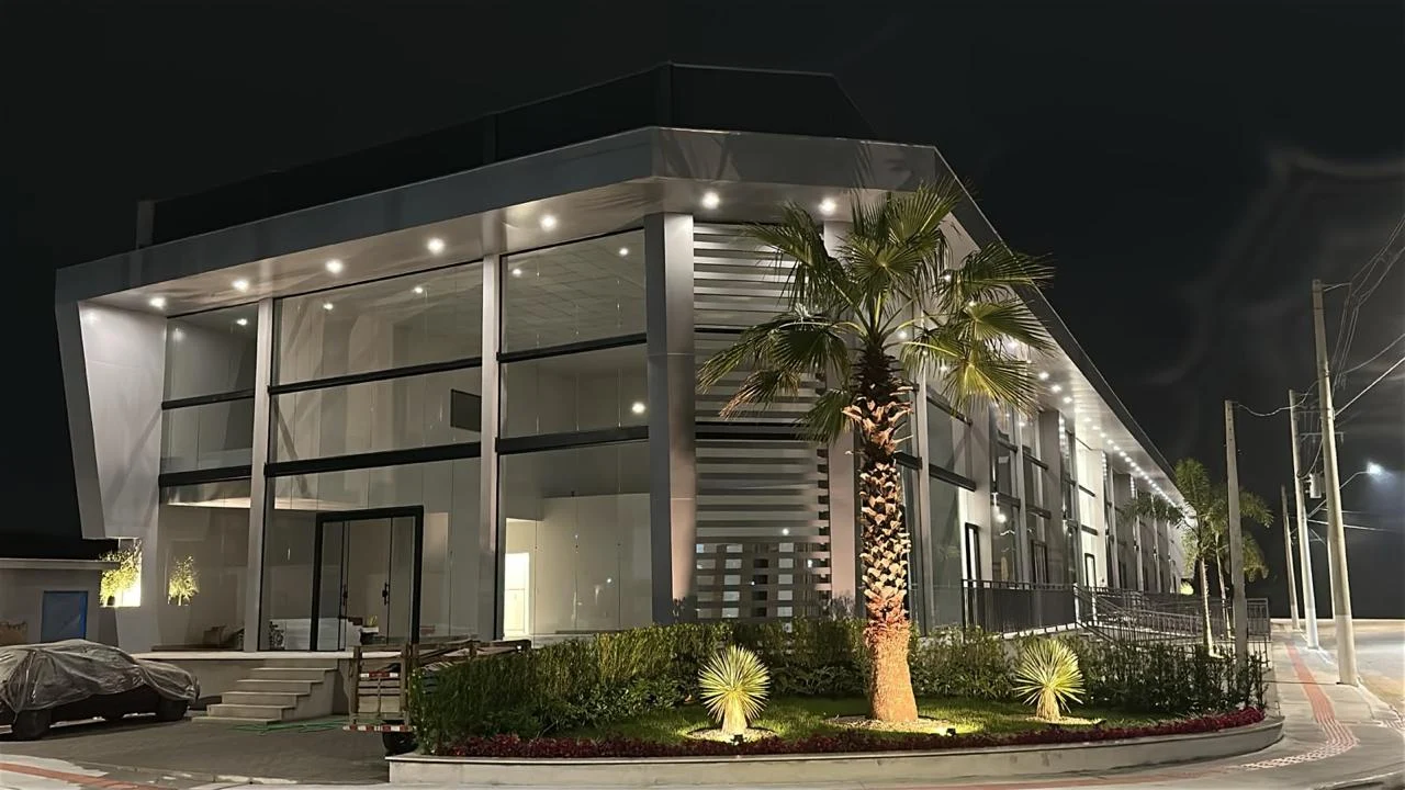 Fachada iluminada do Elyon Business Center, com grandes superfícies de vidro e paisagismo